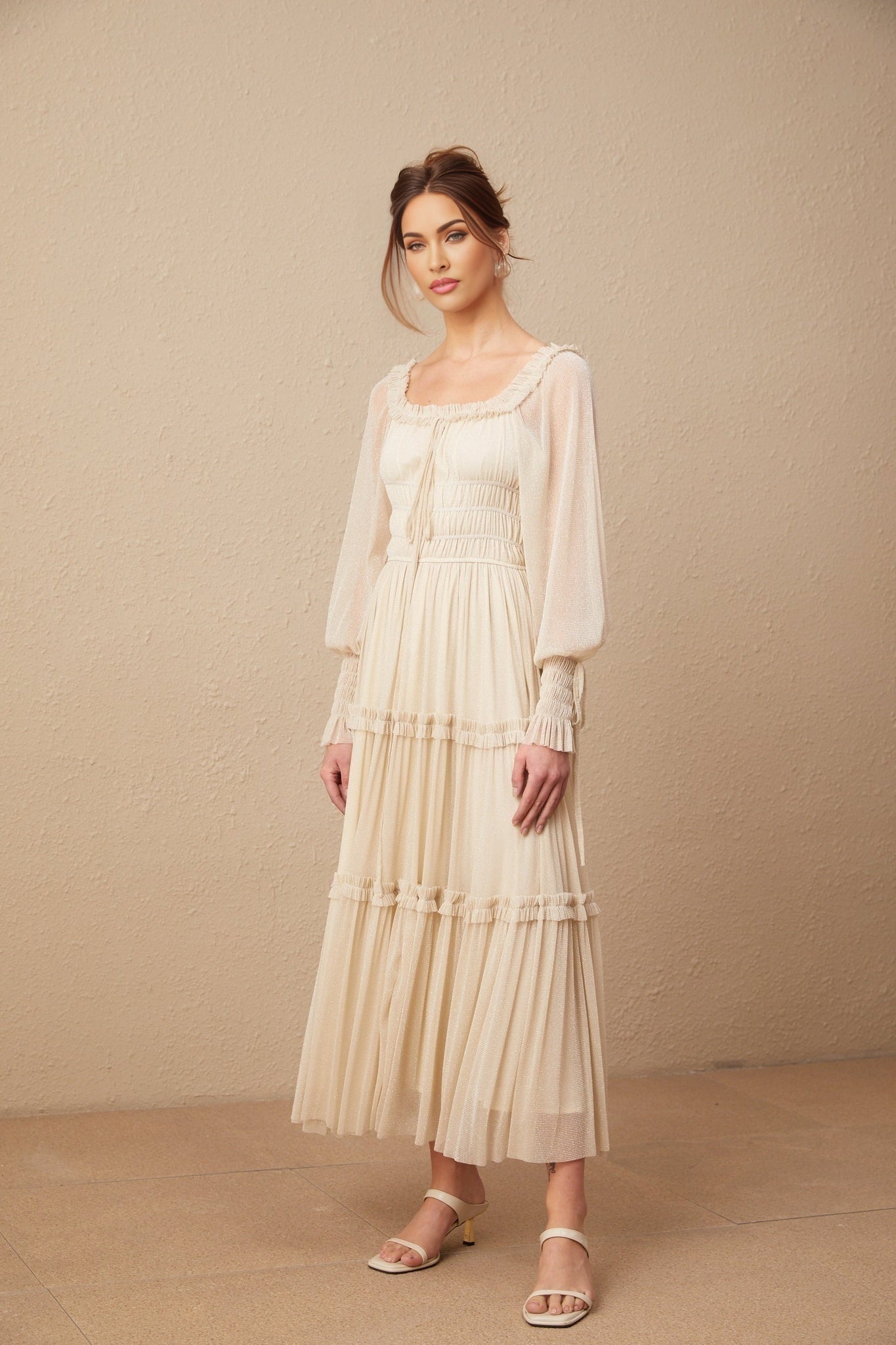 Woman wearing a pleated metallic midi dress with shirred details and a flowy silhouette in a shimmering fabric