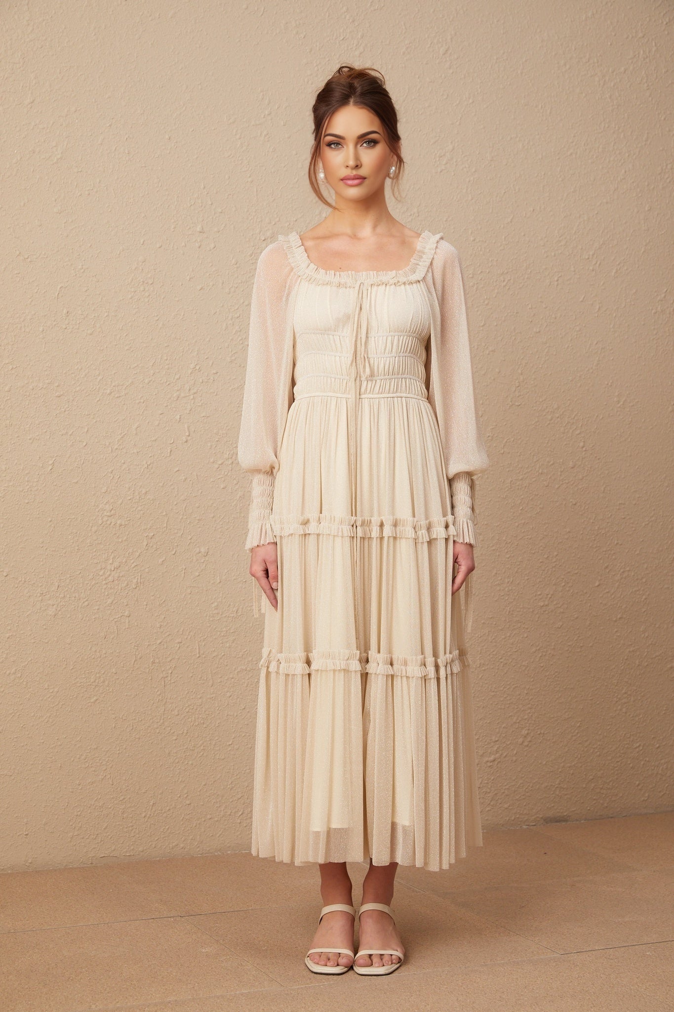 Woman wearing a pleated metallic midi dress with shirred details and a flowy silhouette in a soft gold color