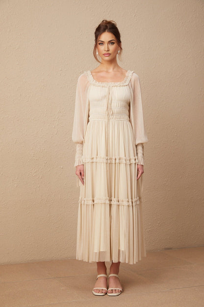 Woman wearing a pleated metallic midi dress with shirred details and a flowy silhouette in a soft gold color