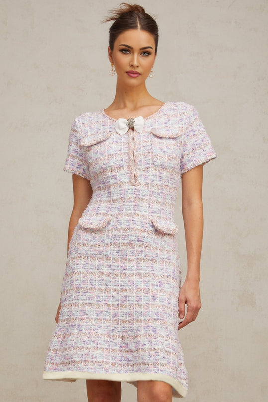 Woman wearing a purple and white checked knit midi dress with long sleeves and a fitted silhouette standing against a plain background