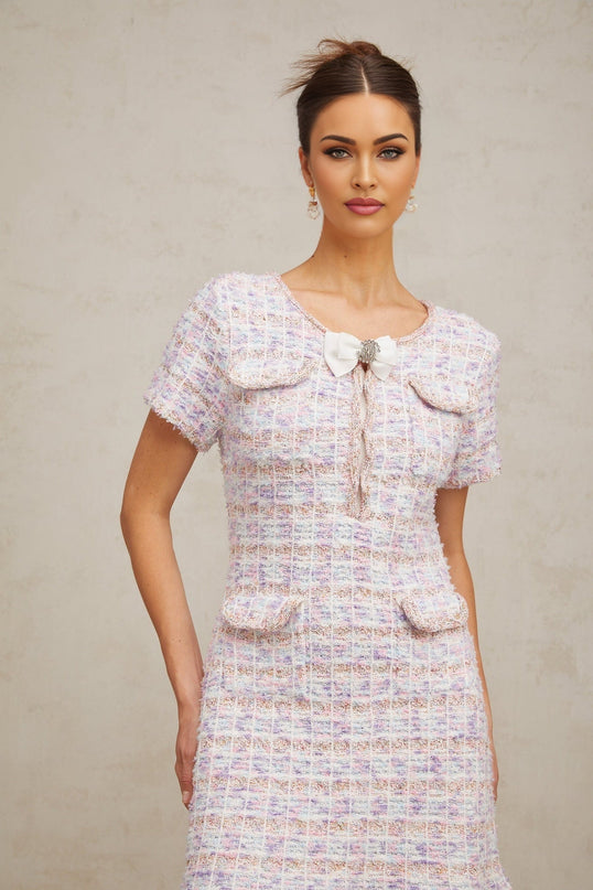 Woman wearing a purple checked knit midi dress with long sleeves standing against a plain background