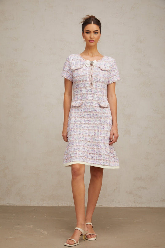 Woman wearing a purple checkered knit midi dress with long sleeves and a fitted silhouette standing against a plain background