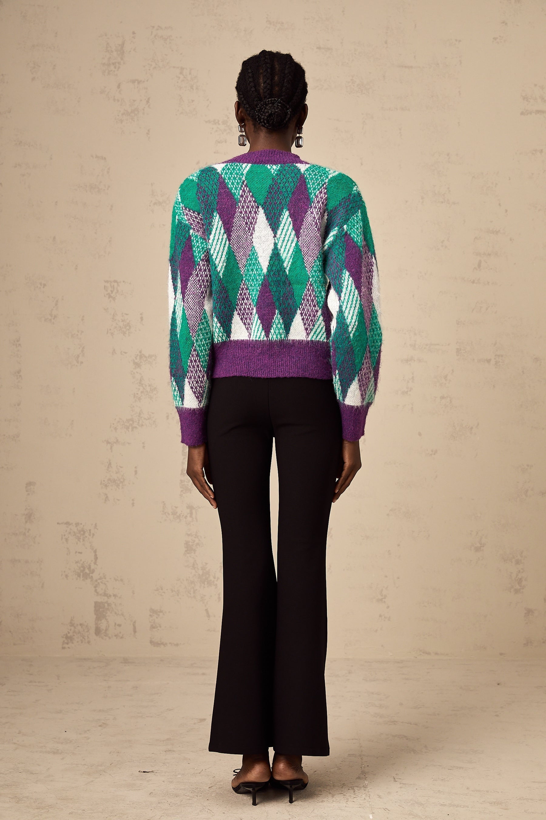 Woman wearing a purple knit top with argyle pattern sleeveless design and crew neck