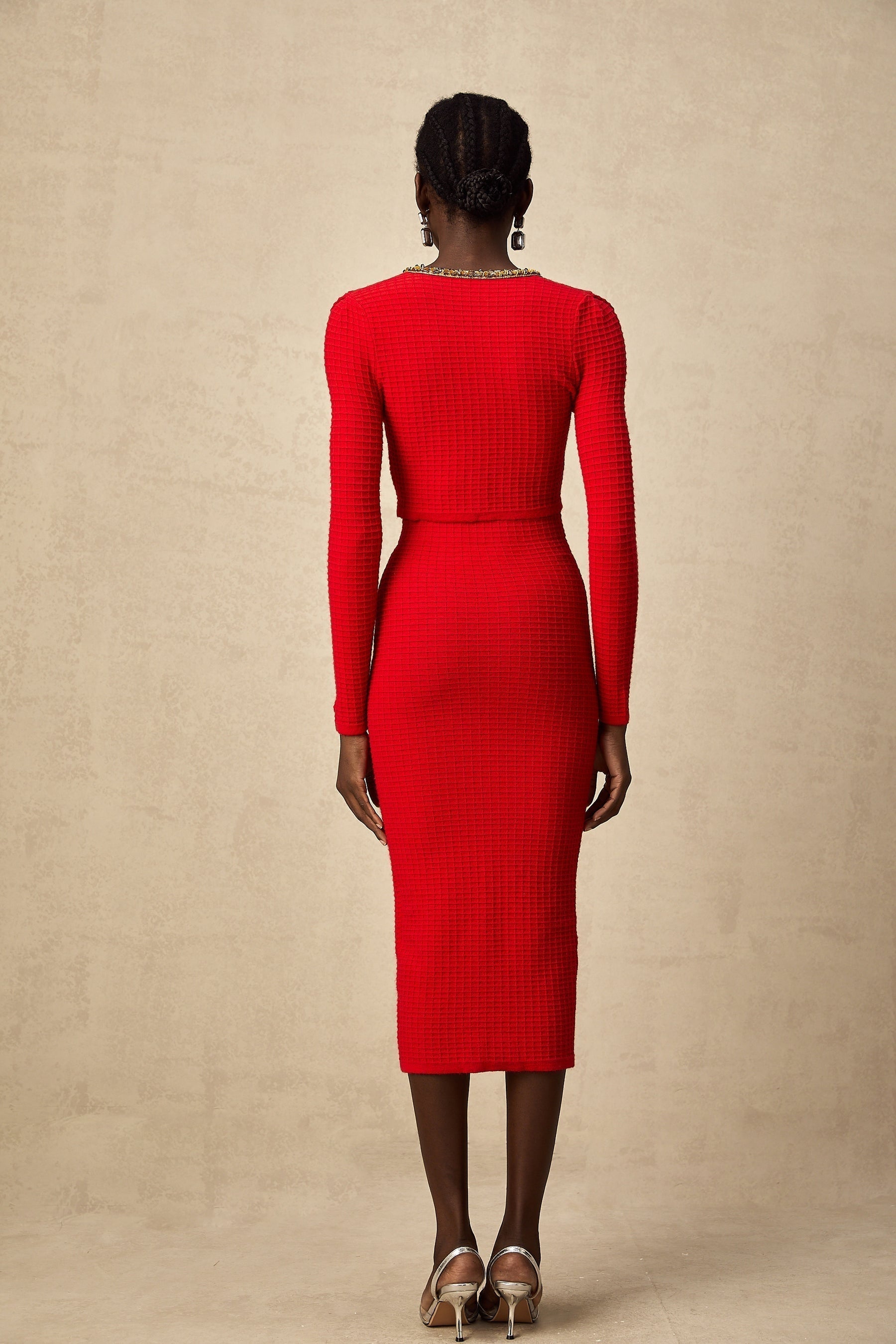Woman wearing a red knitted cardigan and matching skirt set with embellishments named Axelle