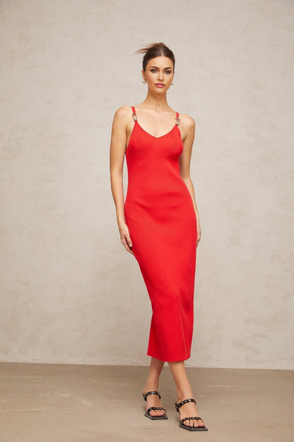 Woman wearing a red knitted midi dress with pin details standing in a neutral pose