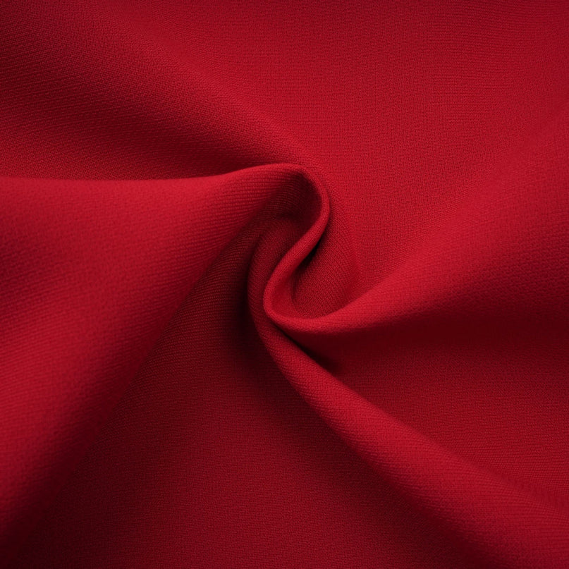 Woman wearing a red pleated blouse and matching skirt set called Colette The top has long sleeves and the skirt falls to just below the knee