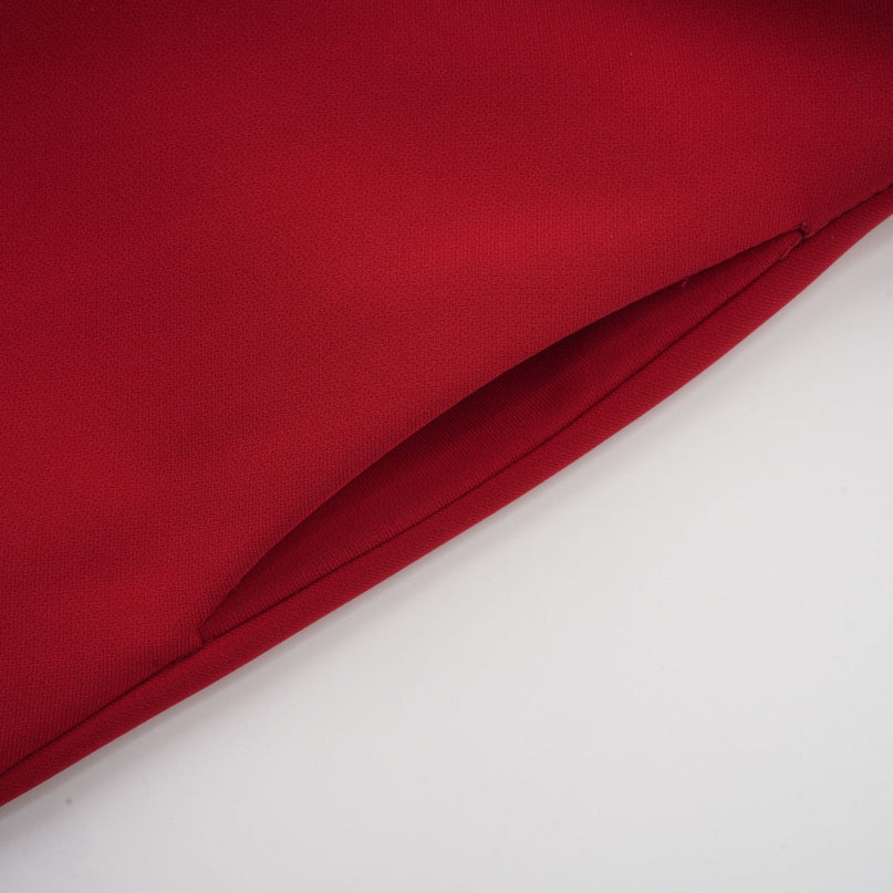 Woman wearing a red pleated blouse and matching skirt set called Colette The top has long sleeves and the skirt falls to mid length creating an elegant coordinated outfit