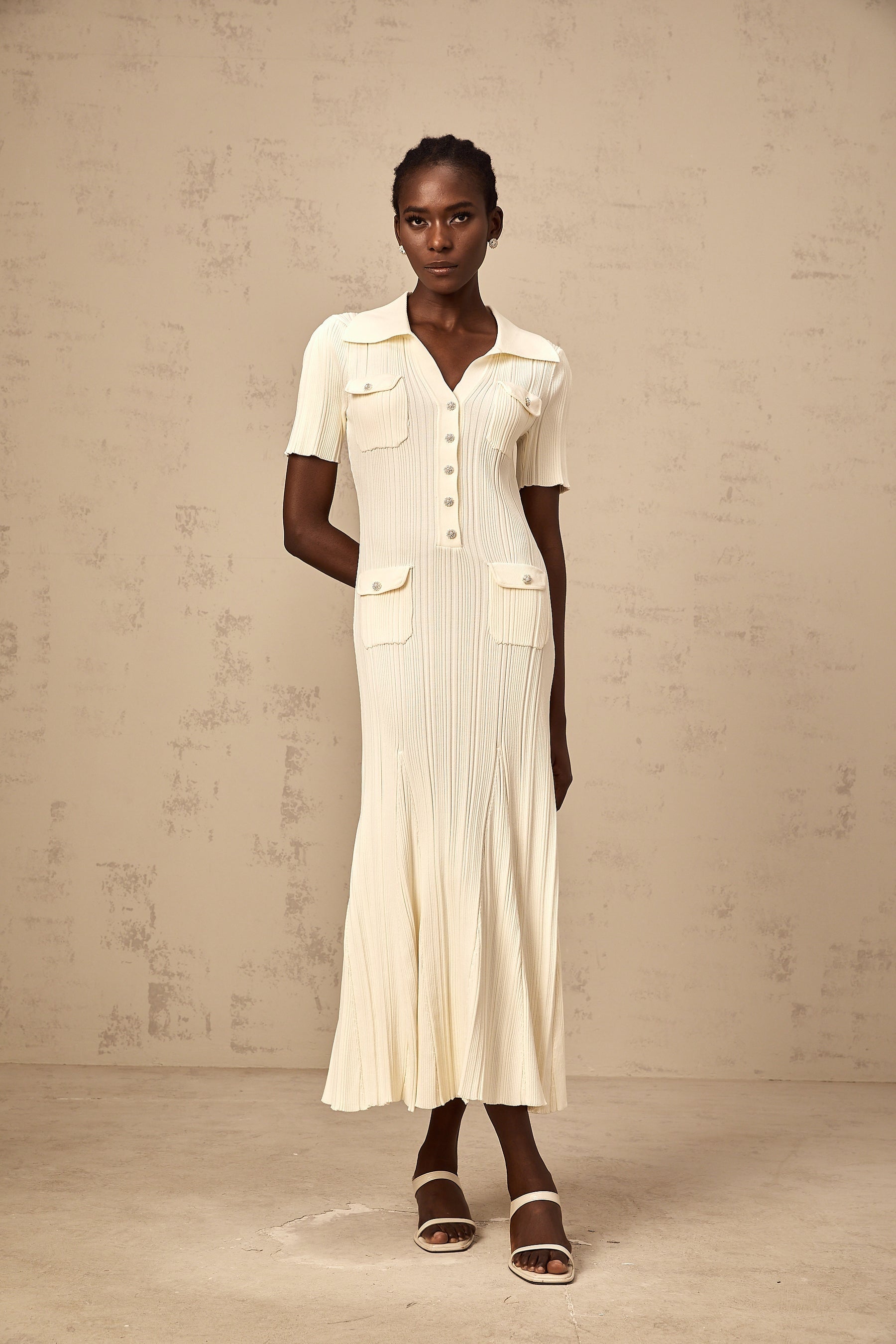 Woman wearing a ribbed knit midi dress in neutral tones standing in a relaxed pose