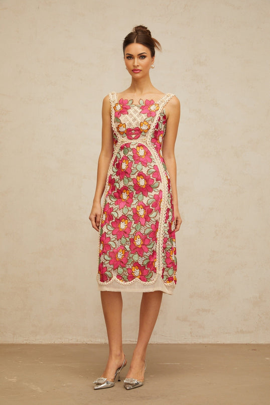 Woman wearing a rosepink midi dress with braided details and floral embroidery standing in a neutral background