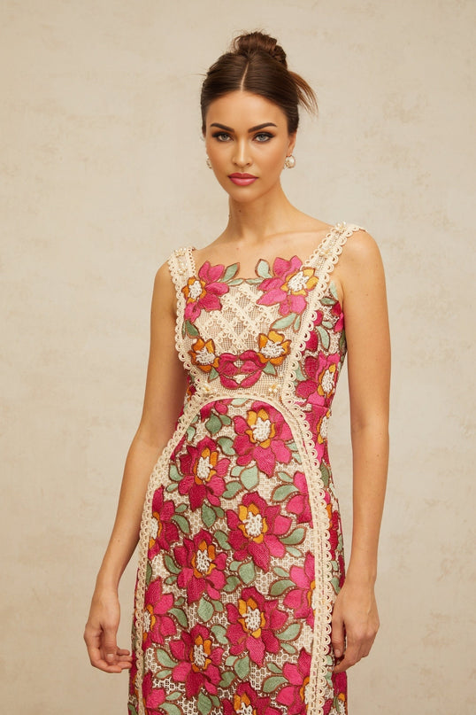 Woman wearing a rosepink midi dress with braided details and floral embroidery standing in a relaxed pose