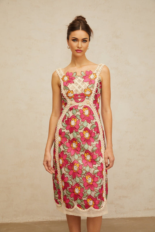 Woman wearing a rosepink midi dress with braided details and floral embroidery