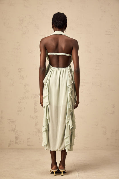 Woman wearing a ruffled midi dress with embellishments and a flowy silhouette in a soft color