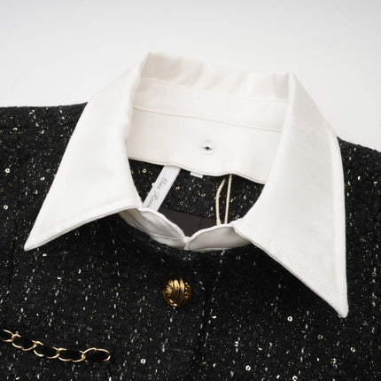 Woman wearing a short black dress with tweed fabric and sequin panels featuring a sleeveless design and fitted silhouette