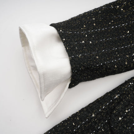 Woman wearing a short black dress with tweed pattern and sequin panels sleeveless design fitted silhouette