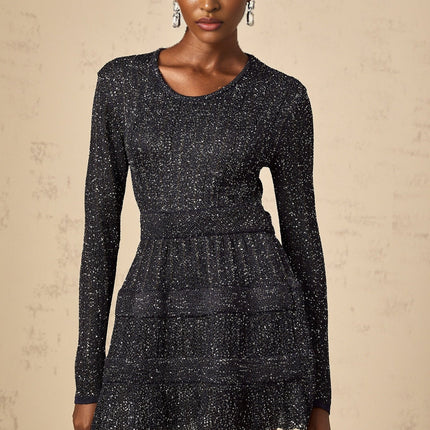 Woman wearing a short black mini dress with sequin embellishments and knit texture