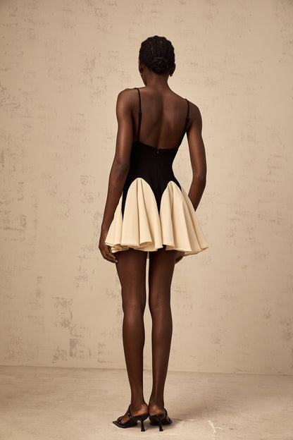Woman wearing a short dress with contrasting color blocks and godet pleats at the hem
