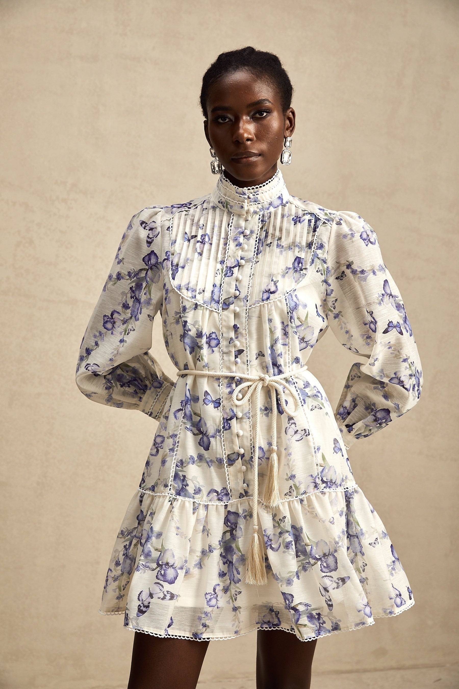 Woman wearing a short flared chiffon dress with a floral print pattern and flowing sleeves