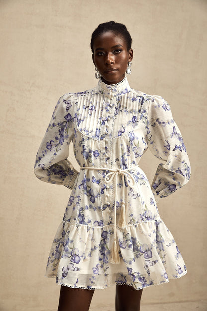 Woman wearing a short flared chiffon dress with a floral print pattern and flowing sleeves