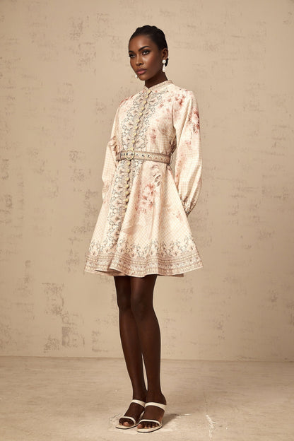 Woman wearing a short floral print dress with a belt cinched at the waist