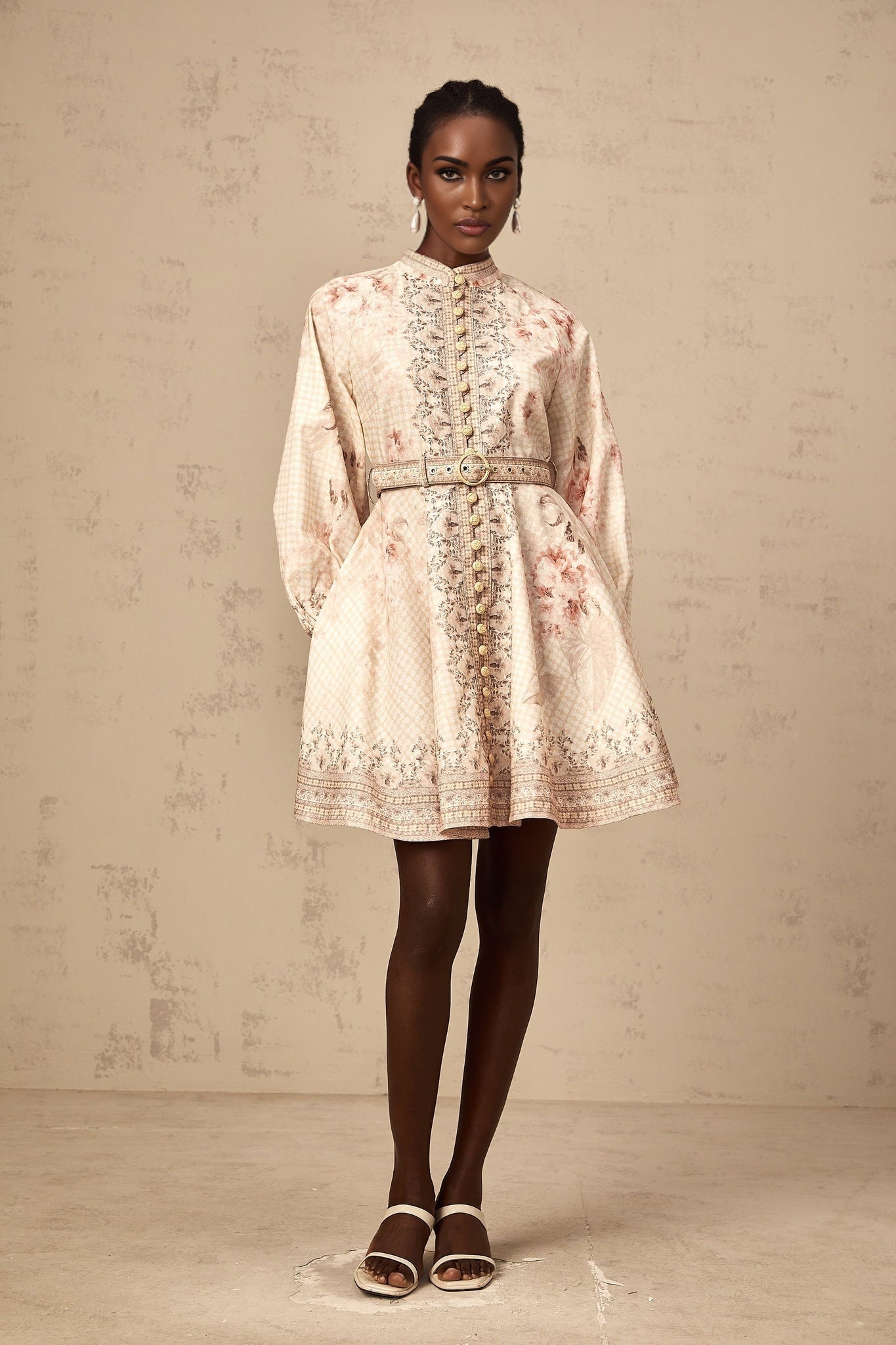 Woman wearing a short floral print dress with a belt cinching the waist