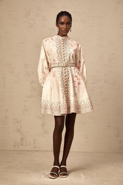 Woman wearing a short floral print dress with a belt cinching the waist