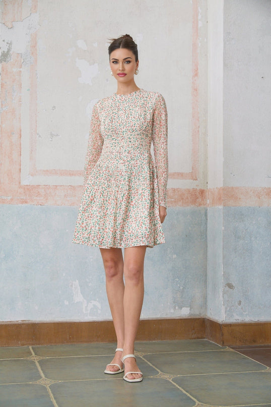 Woman wearing a short floral print dress with pleats and a Marion style design