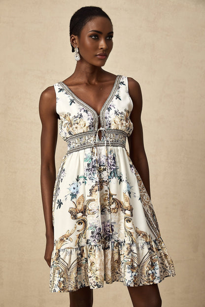 Woman wearing a short floral print dress with vneck in vibrant colors against a plain background
