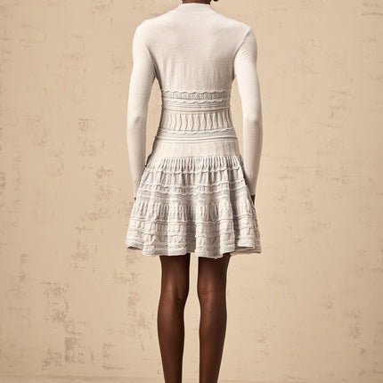 Woman wearing a short grey dress with ruffle details and ribbed texture