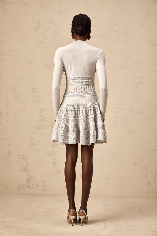 Woman wearing a short grey dress with ruffle details and ribbed texture