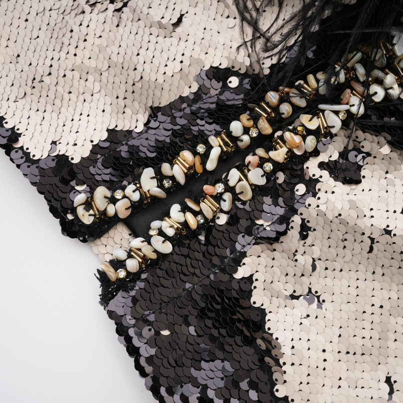 Woman wearing a short jacket with sequins and feather embellishments shimmering in the light