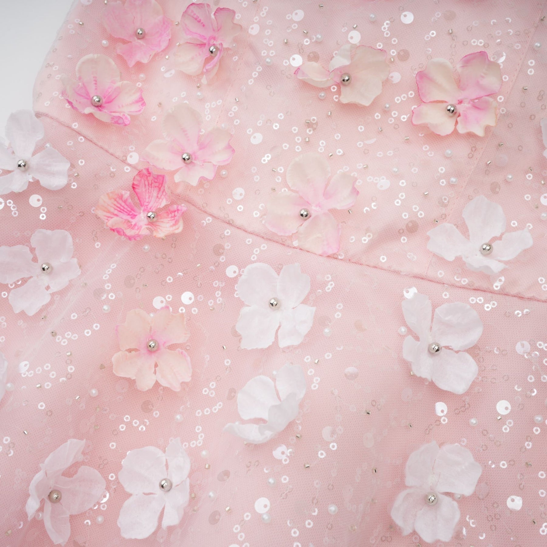 Woman wearing a short pink dress with three dimensional floral petal details and a puffy silhouette