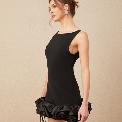 Woman wearing a short ruffled dress with an open back design