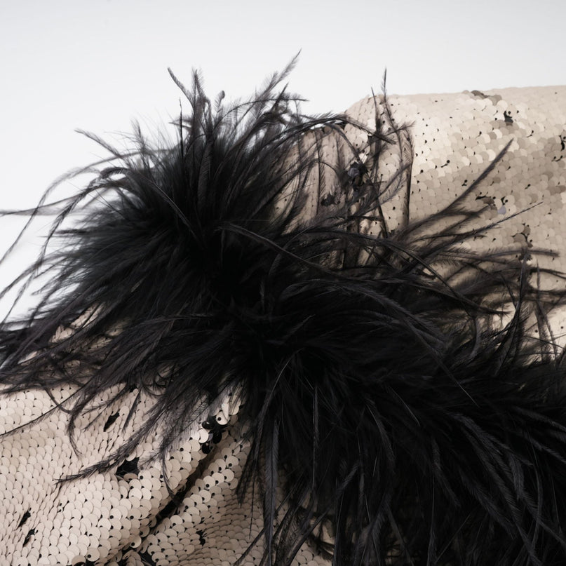 Woman wearing a short shimmering jacket adorned with sequins and feather embellishments