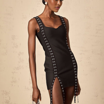 Woman wearing a short tight fitting black bandage dress with hook and eye closures