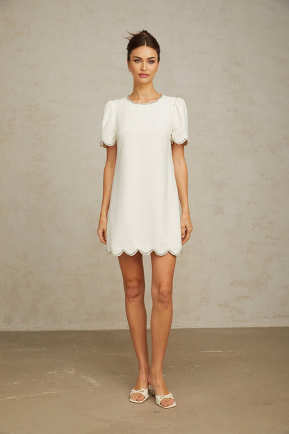 Woman wearing a short white dress adorned with crystal embellishments