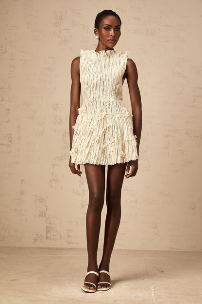 Woman wearing a short white lace dress with semisheer fabric and creased texture standing in a relaxed pose