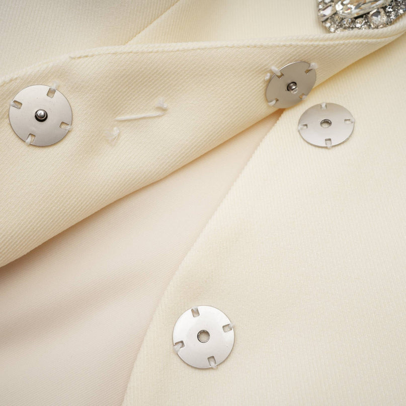 Woman wearing a sparkling jacket and matching shorts set with crystal embellishments in a glamorous pose