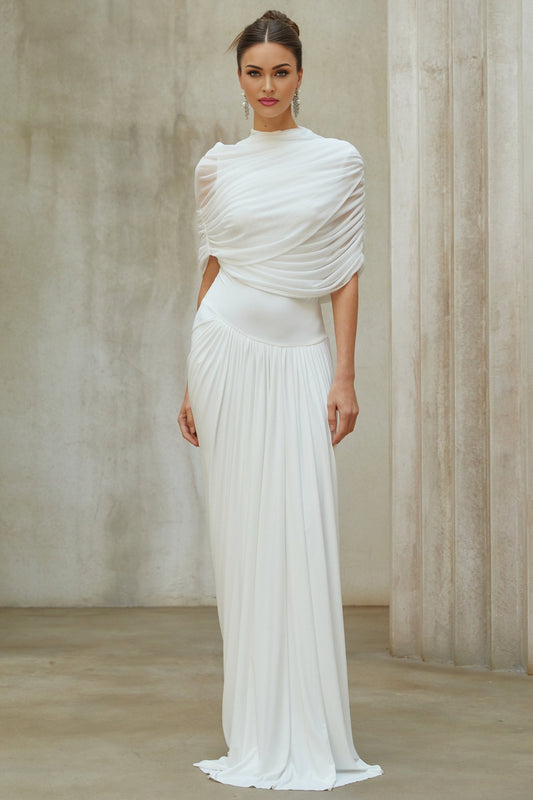 Woman wearing a white asymmetrical pleated maxi dress with long flowing skirt and one shoulder design
