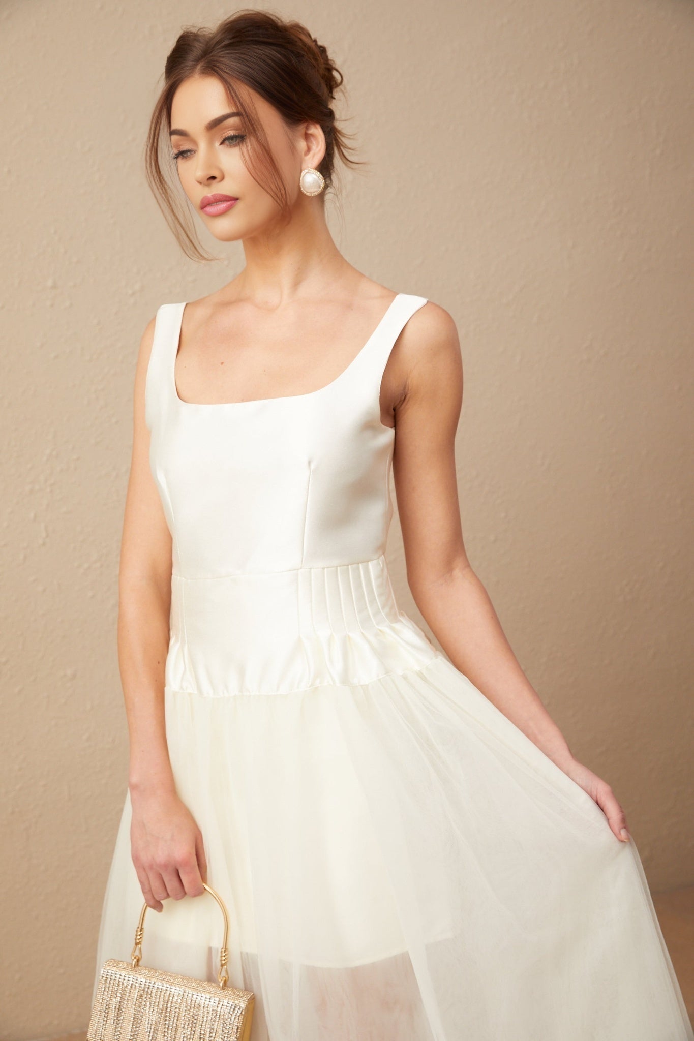 Woman wearing a white floor length dress with satin bodice and tulle skirt panels