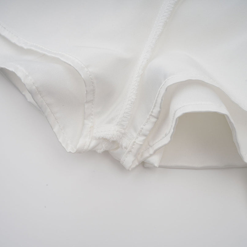 Woman wearing a white halterneck mini dress with ruffled details and a fitted silhouette