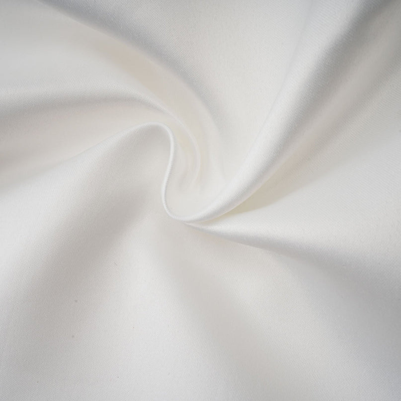 Woman wearing a white halterneck mini dress with ruffles and a fitted silhouette standing against a plain background