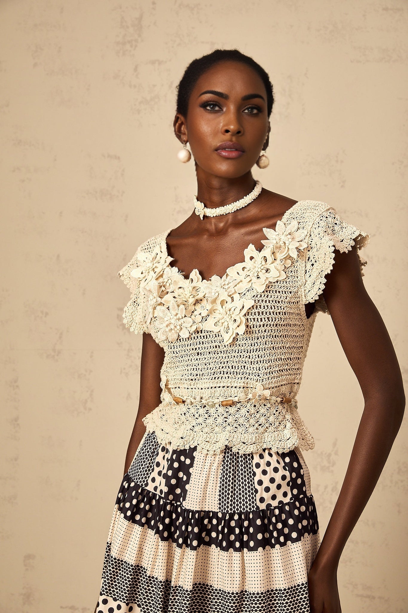 Woman wearing a white knit top with colorful 3D floral beaded embellishments on the front