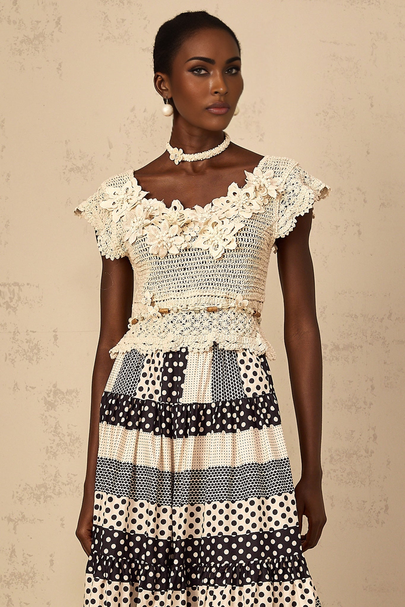 Woman wearing a white knit top with colorful 3D floral beaded embellishments