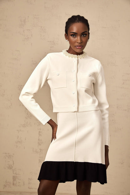 Woman wearing a white knitted cardigan adorned with faux pearls