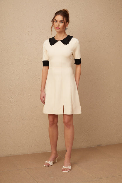 Woman wearing a white knitted mini dress with split hem detail and short sleeves
