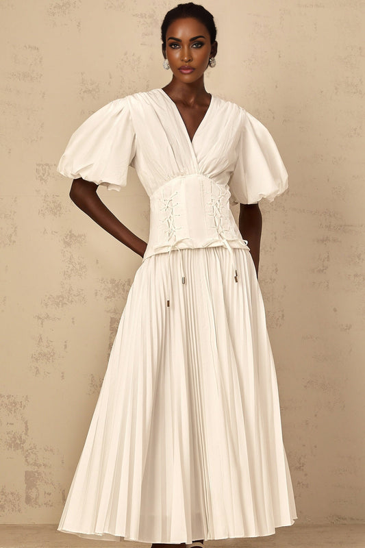 Woman wearing a white lace up pleated maxi dress standing outdoors