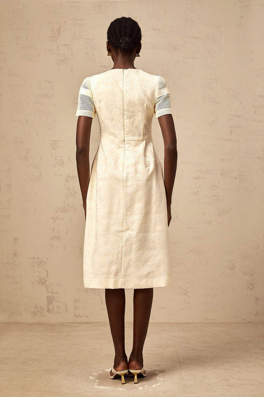 Woman wearing a white midi dress with floral embroidery and openwork details