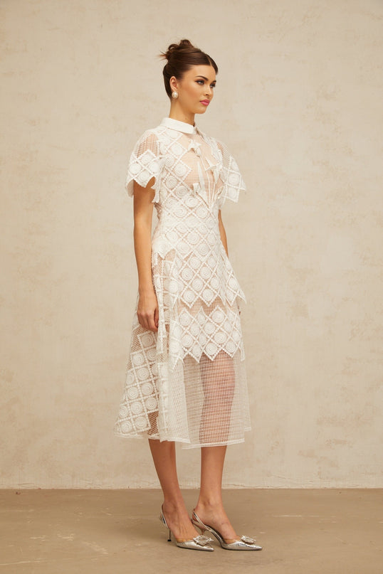 Woman wearing a white midi dress with floral embroidery details named Yasmine