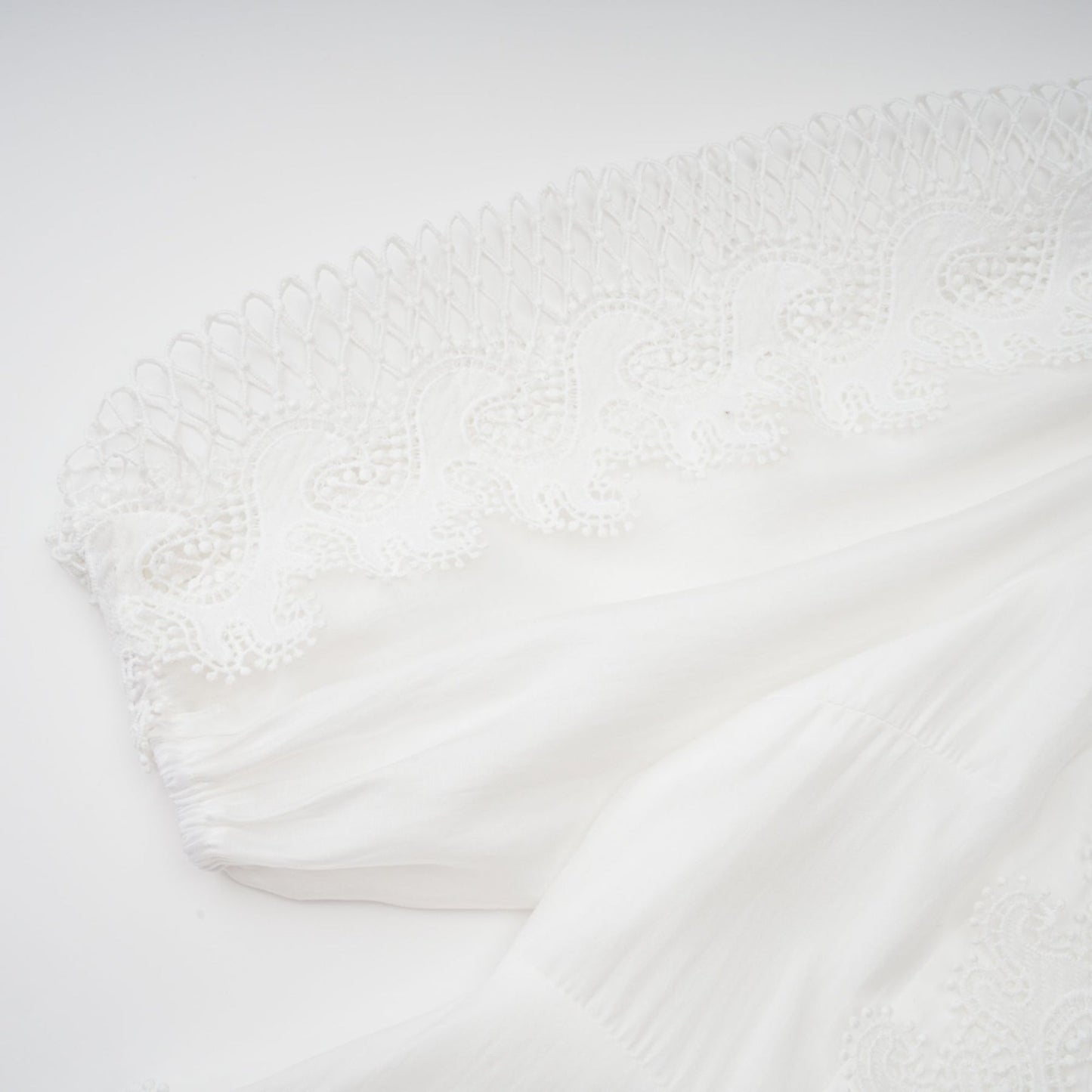Woman wearing a white midi dress with lace trim panels and a belt at the waist