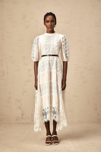 Woman wearing a white midi dress with lace trim panels and a belt at the waist